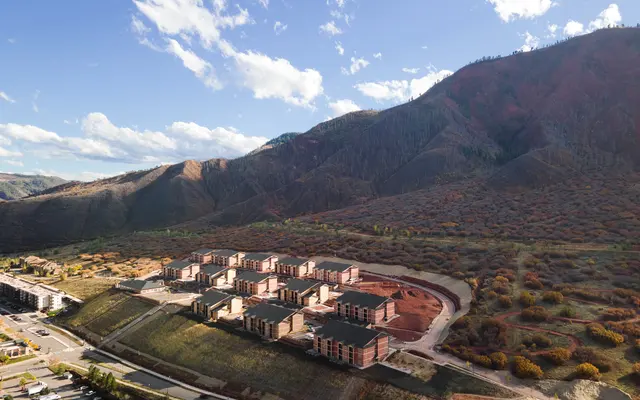 Aerial view of a construction site surrounded by mountain landscape and blue skies.