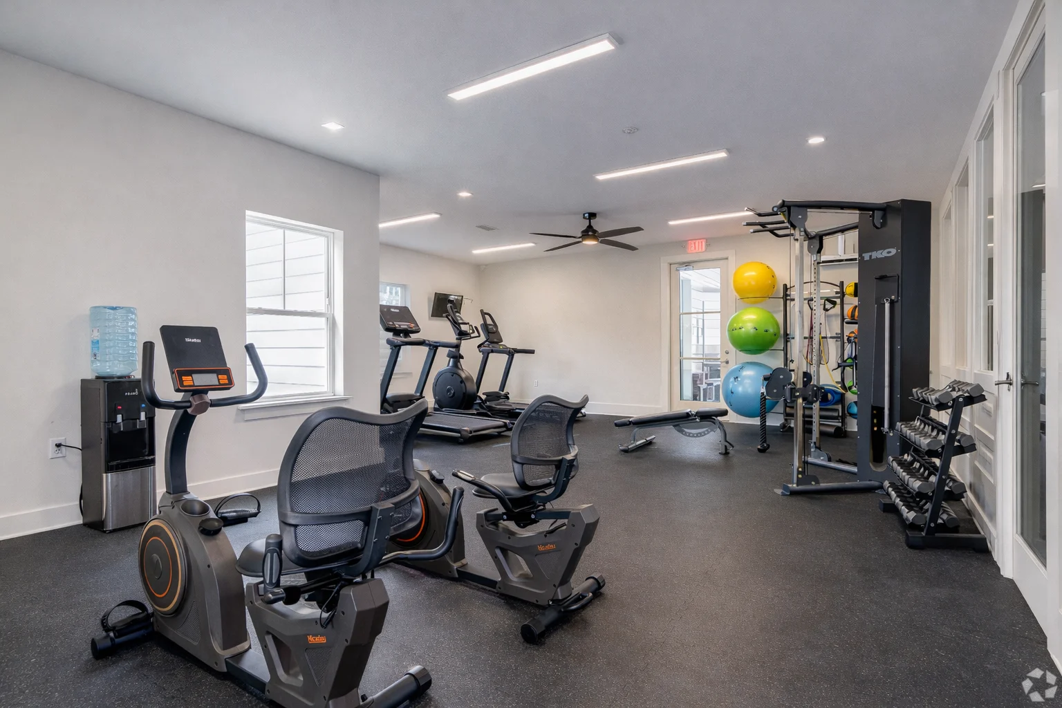 Modern Gym Interior Interior view of a modern gym featuring various exercise equipment including stationary bikes, a weight machine, colorful exercise balls, and a water dispenser.