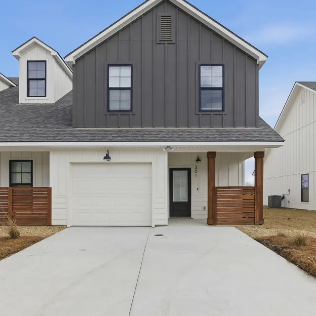 Modern House Exterior A modern two-story house with a gray and white exterior, featuring a garage and wooden accents at the entrance.