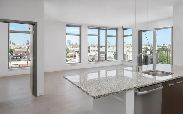 Bright, empty modern kitchen with island and large windows overlooking the city.