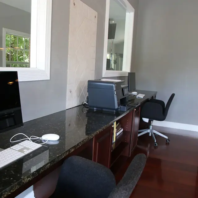 Workstations with computers on a long table with two chairs and a printer.