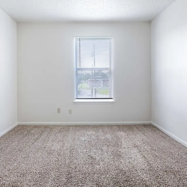 An empty room with carpet flooring and a window.