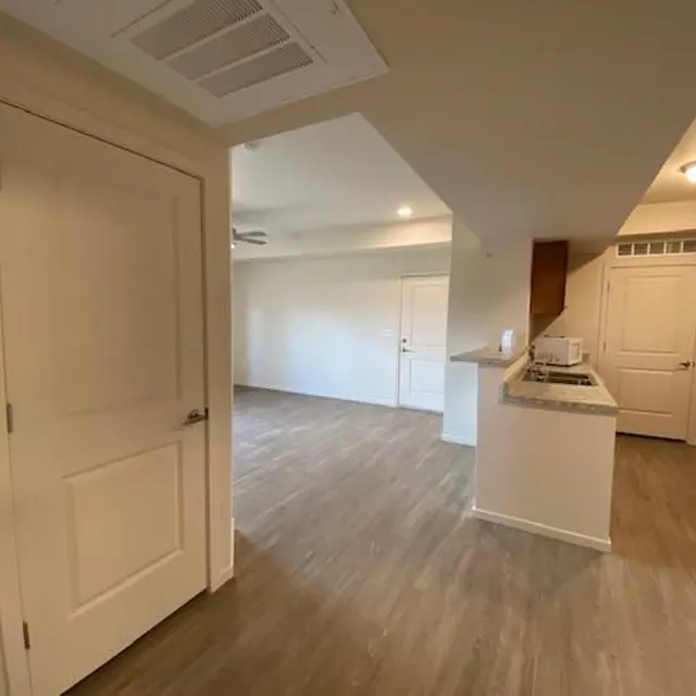 Interior view of a modern apartment showcasing a living space, kitchen area, and entry door.