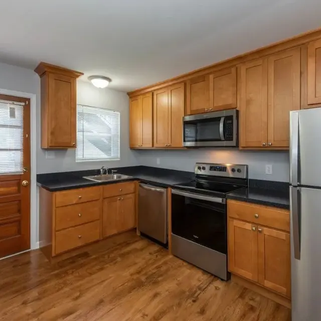 A modern kitchen featuring wooden cabinets, stainless steel appliances, and a door leading outside.