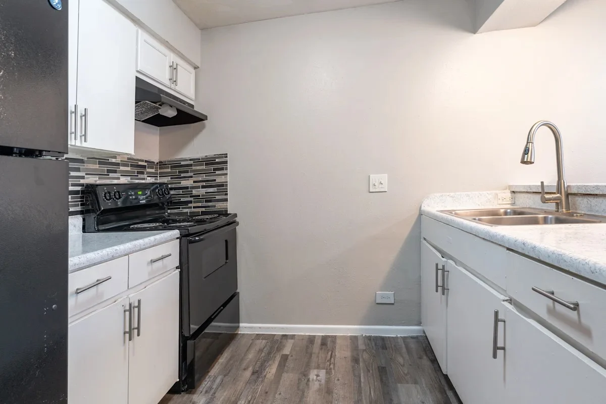 Modern Kitchen Design A modern kitchen featuring white cabinetry, a black stove, and a sink with a faucet. The walls are painted a light color, and a tiled backsplash adds texture.