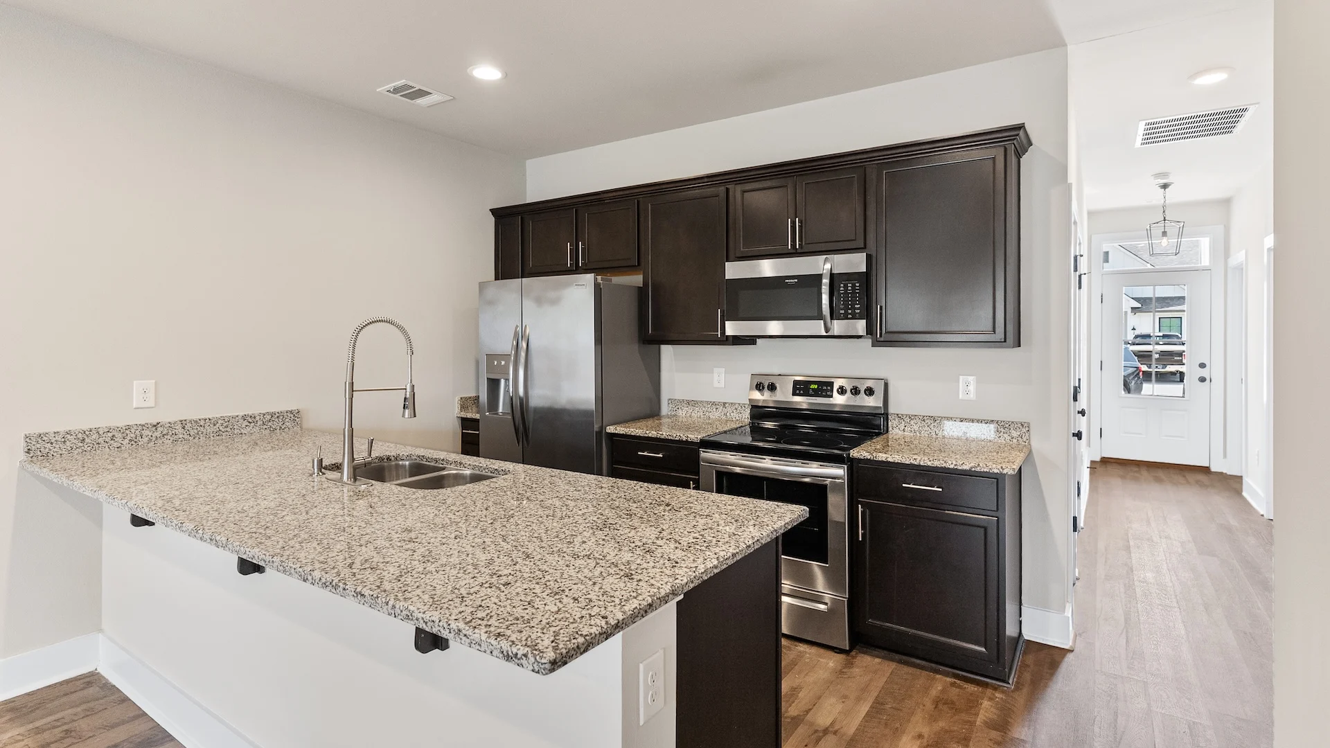Modern Kitchen Design A modern kitchen featuring dark wood cabinetry, stainless steel appliances, and a granite countertop island with a sink.