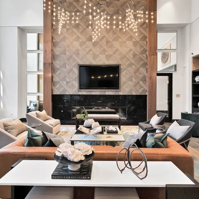 Stylish Modern Living Room A modern and stylish living room featuring a large window, elegant furnishings, and a decorative wall with a TV. There are stylish chairs, a coffee table with decorative items, and warm lighting from a unique chandelier.