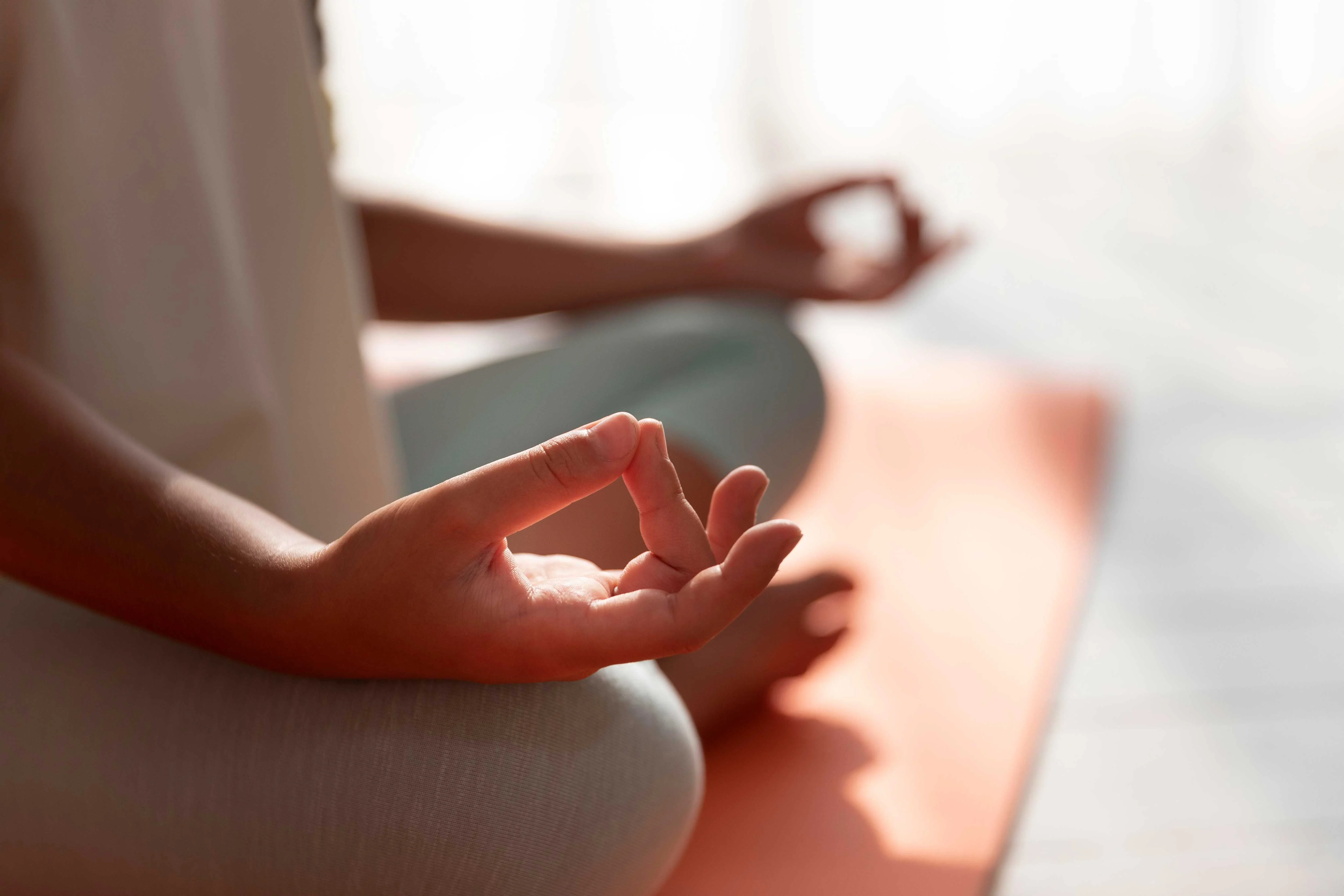 Close-up of hands in a meditative pose on a yoga mat.