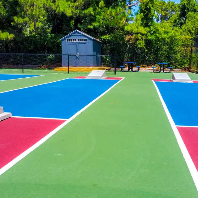 View of brightly colored tennis courts with two ramps and a shed in the background.