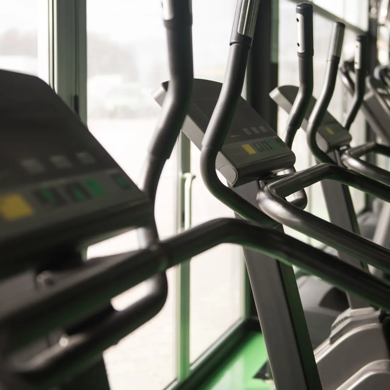 Row of elliptical machines in a gym with large windows