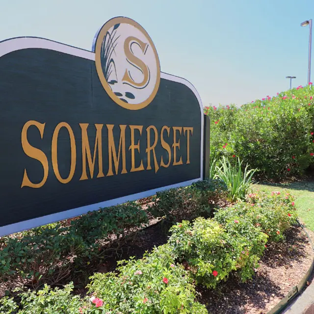 A sign that reads 'SOMMERSET' with a decorative letter 'S' and surrounded by greenery.