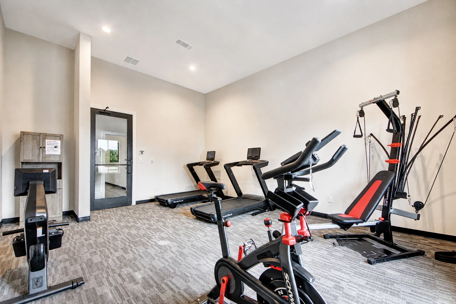 Modern Gym Interior A modern gym featuring various exercise equipment including treadmills, a stationary bike, and a weight machine, with large windows allowing natural light.