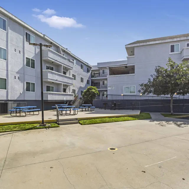View of an apartment complex courtyard with buildings on either side and outdoor seating.