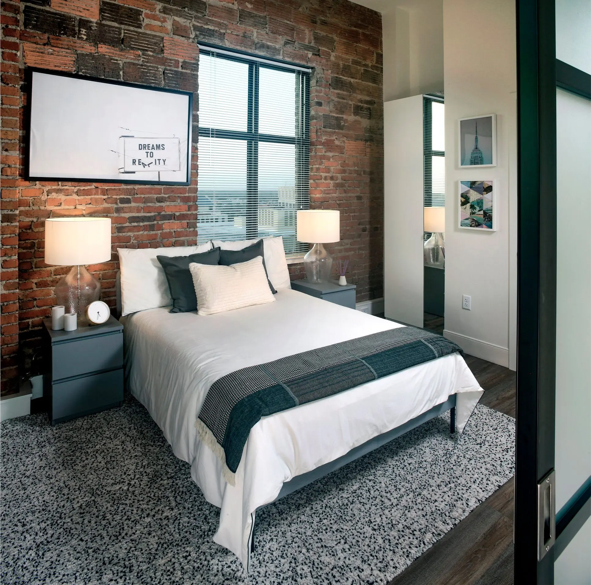 Stylish Urban Bedroom A stylish bedroom featuring exposed brick walls, a cozy bed with decorative pillows, bedside tables with lamps, and decorative art on the walls.