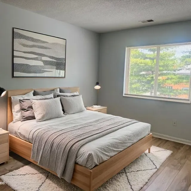 A modern, virtually staged bedroom featuring a wooden bed with gray and white bedding, bedside tables with lamps, and a large window letting in natural light.
