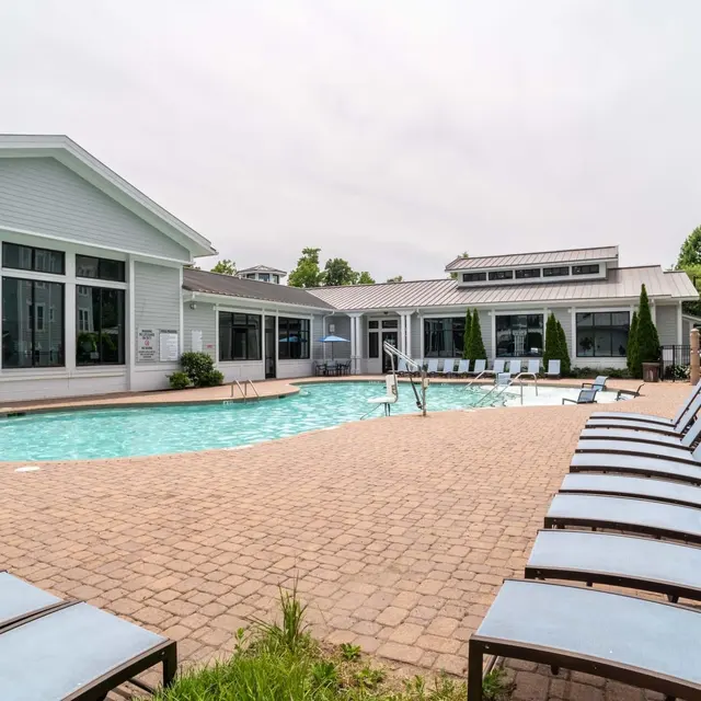 A serene pool area surrounded by lounge chairs and modern buildings.