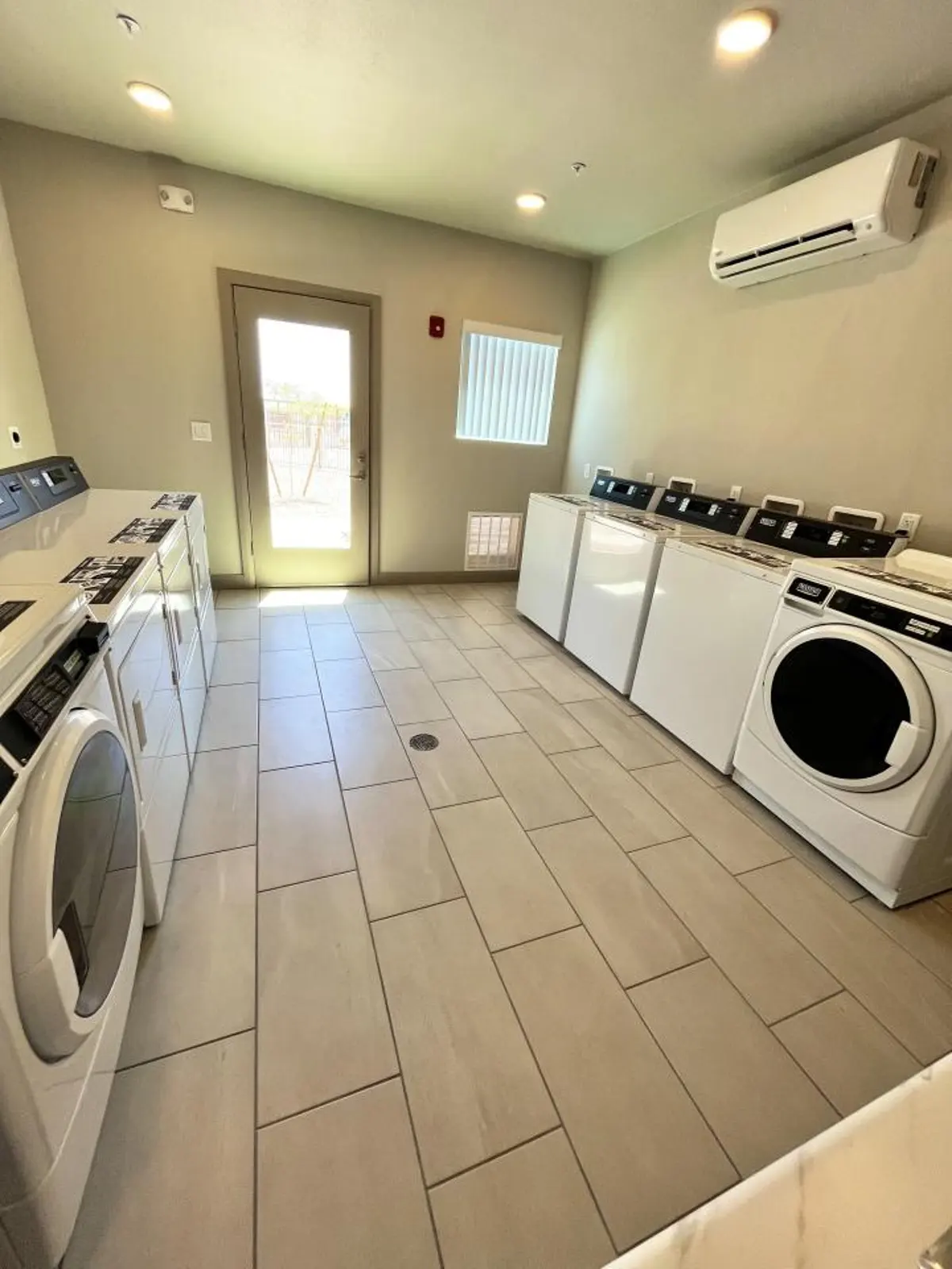 Laundry room with rows of washers and dryers.