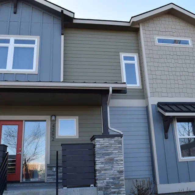 Modern Townhouse Exterior A modern townhouse with a mix of siding colors, featuring a red front door and stone accents.