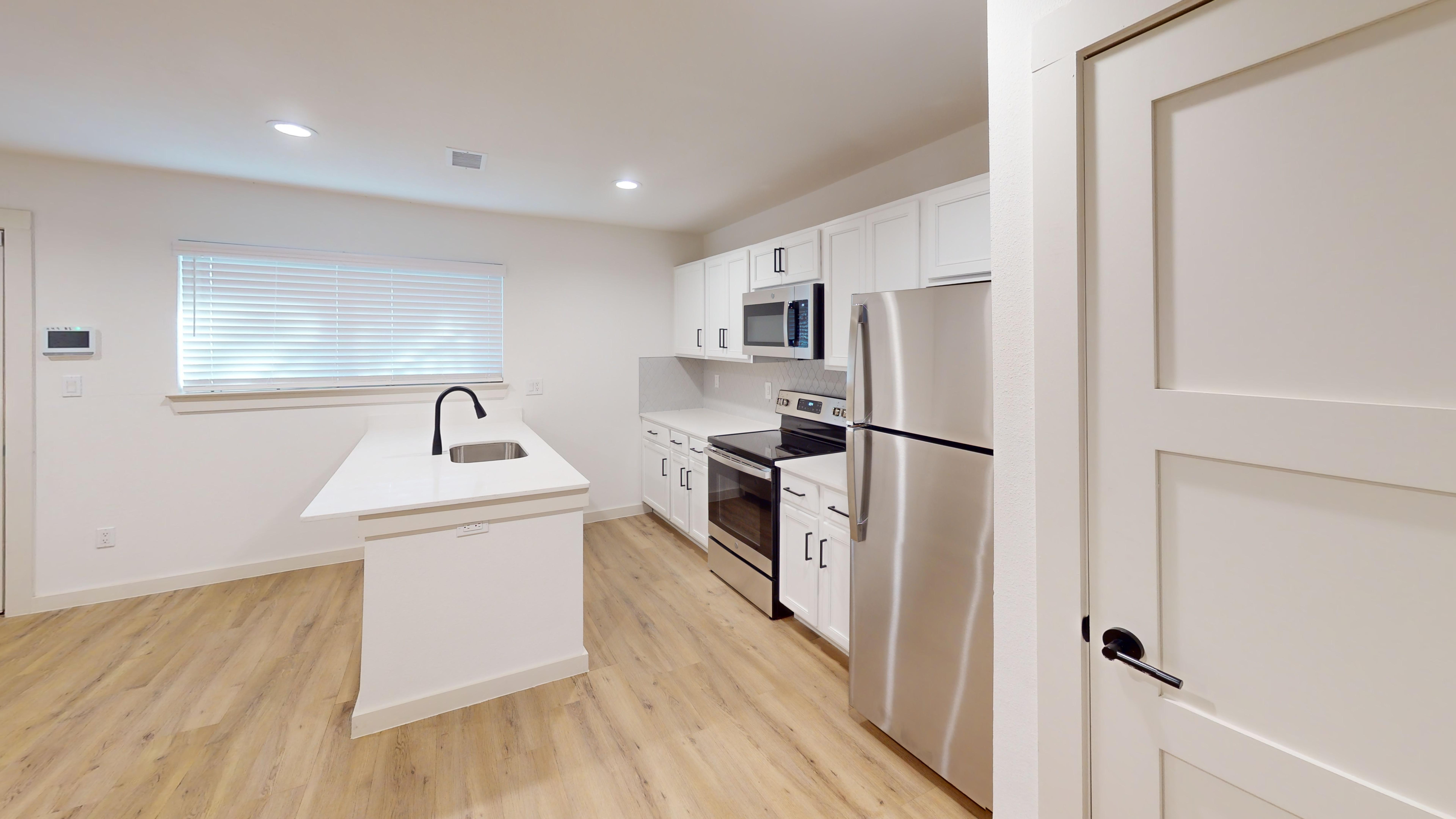 Contemporary Kitchen Design A modern kitchen with white cabinetry, stainless steel appliances, and a countertop island with a sink.