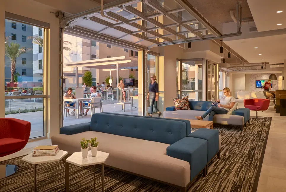 Contemporary Lobby Design A modern and inviting lobby area featuring blue and gray sofas, stylish furniture, large windows letting in natural light, and people interacting in the background.