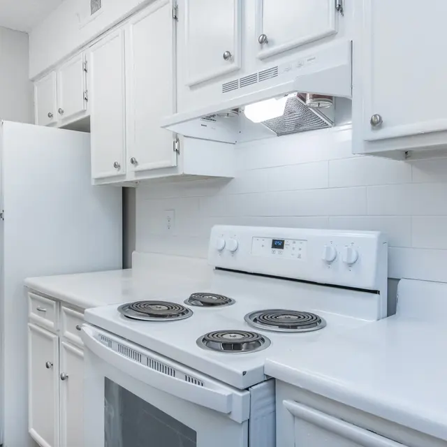 A bright, modern kitchen with white cabinets and appliances.