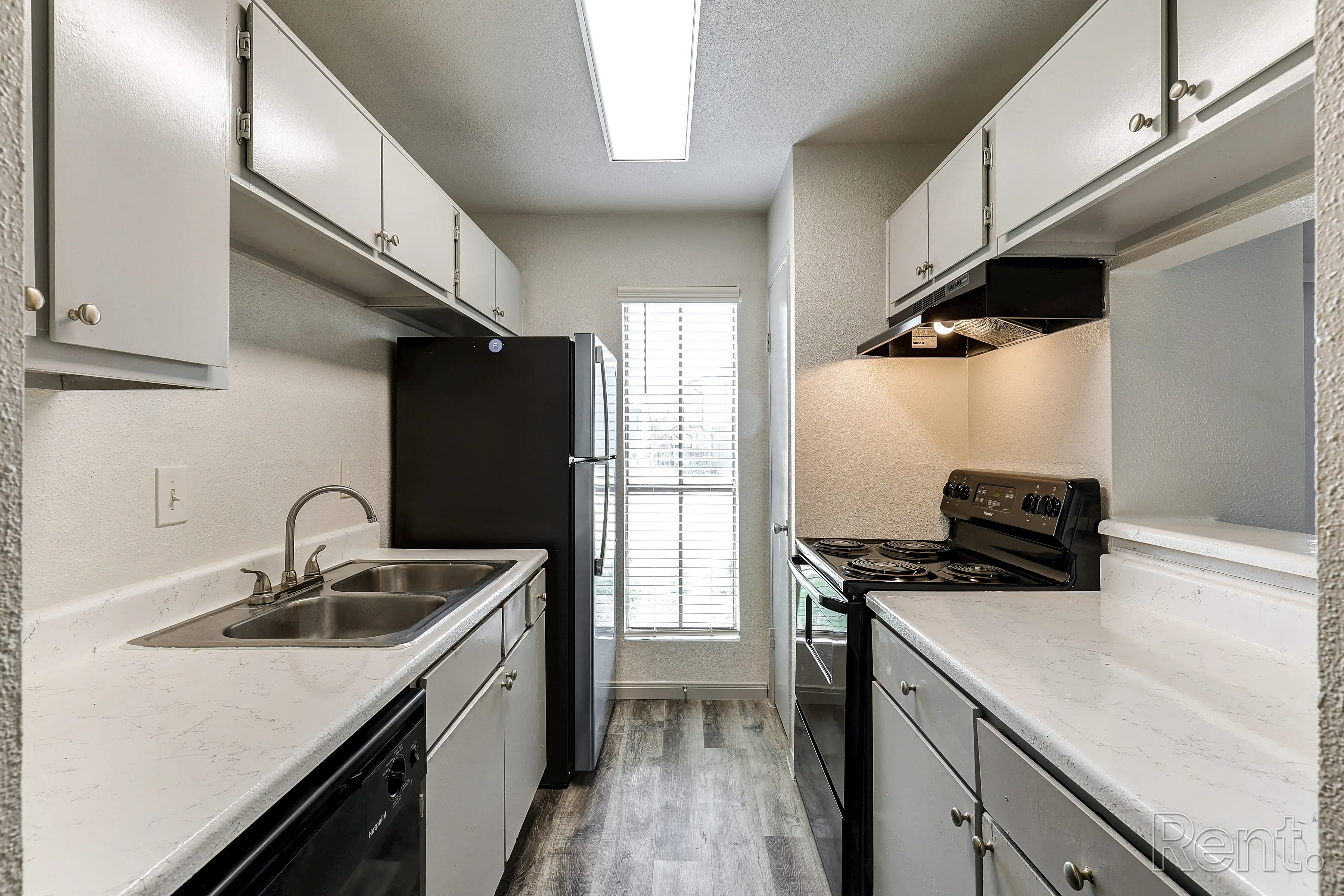 Stylish Modern Kitchen Interior view of a modern kitchen with white cabinets, black appliances, and a window letting in natural light.