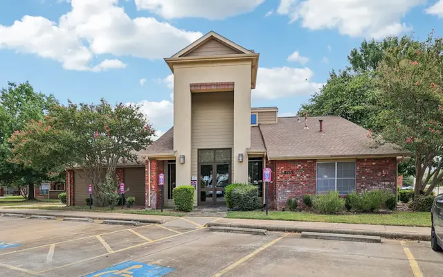 Front View of a Residential Building Front view of a brick building with a peaked roof and landscaped surroundings.