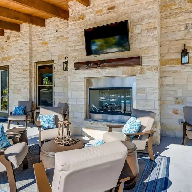 Stylish outdoor lounge area with stone walls, comfortable seating, and a fireplace.