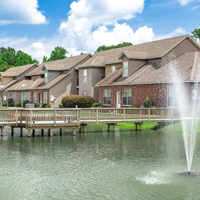 Scenic view of a lake with a fountain and residential apartments along the shore.