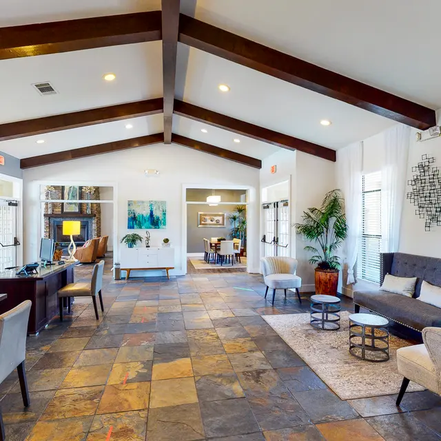 Modern Lobby Interior A spacious modern lobby with high ceilings, wooden beams, and stone flooring. The area features a reception desk, comfortable seating arrangements, and decorative elements including plants and artwork.