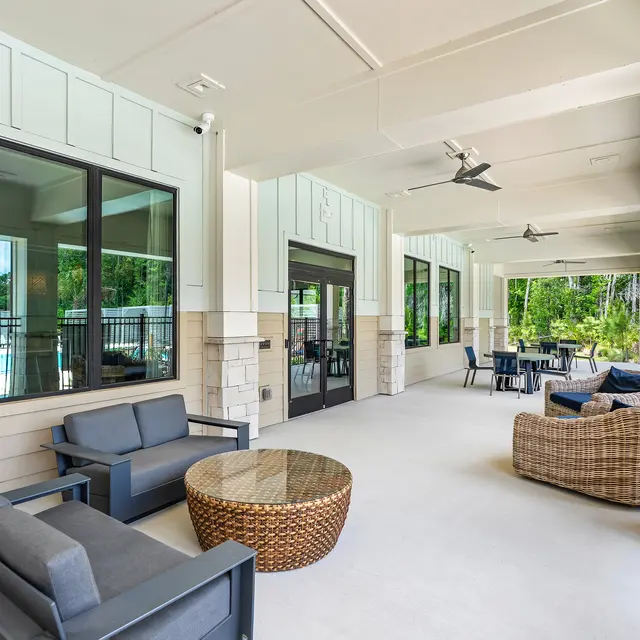 Outdoor Lounge Area A spacious outdoor lounge area featuring comfortable seating, a round coffee table, and large windows showing a green landscape outside.