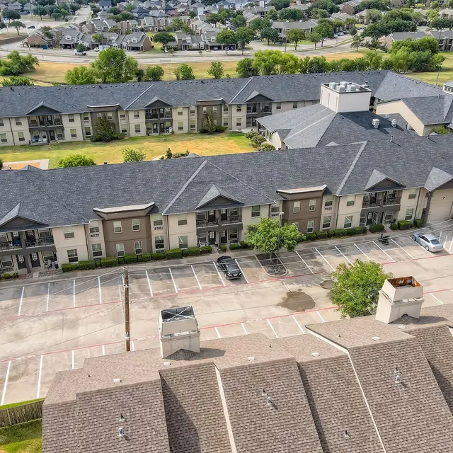 Aerial view of a modern apartment complex with multiple buildings and a parking lot.
