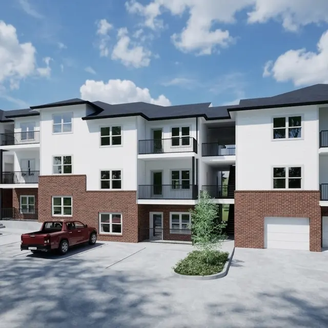 A modern apartment building with a combination of white and brick exteriors, featuring multiple balconies and a parking lot in front.