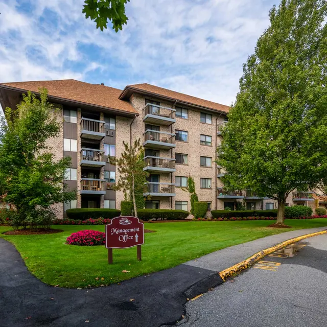 Exterior view of a multi-story apartment building surrounded by greenery and landscaping.