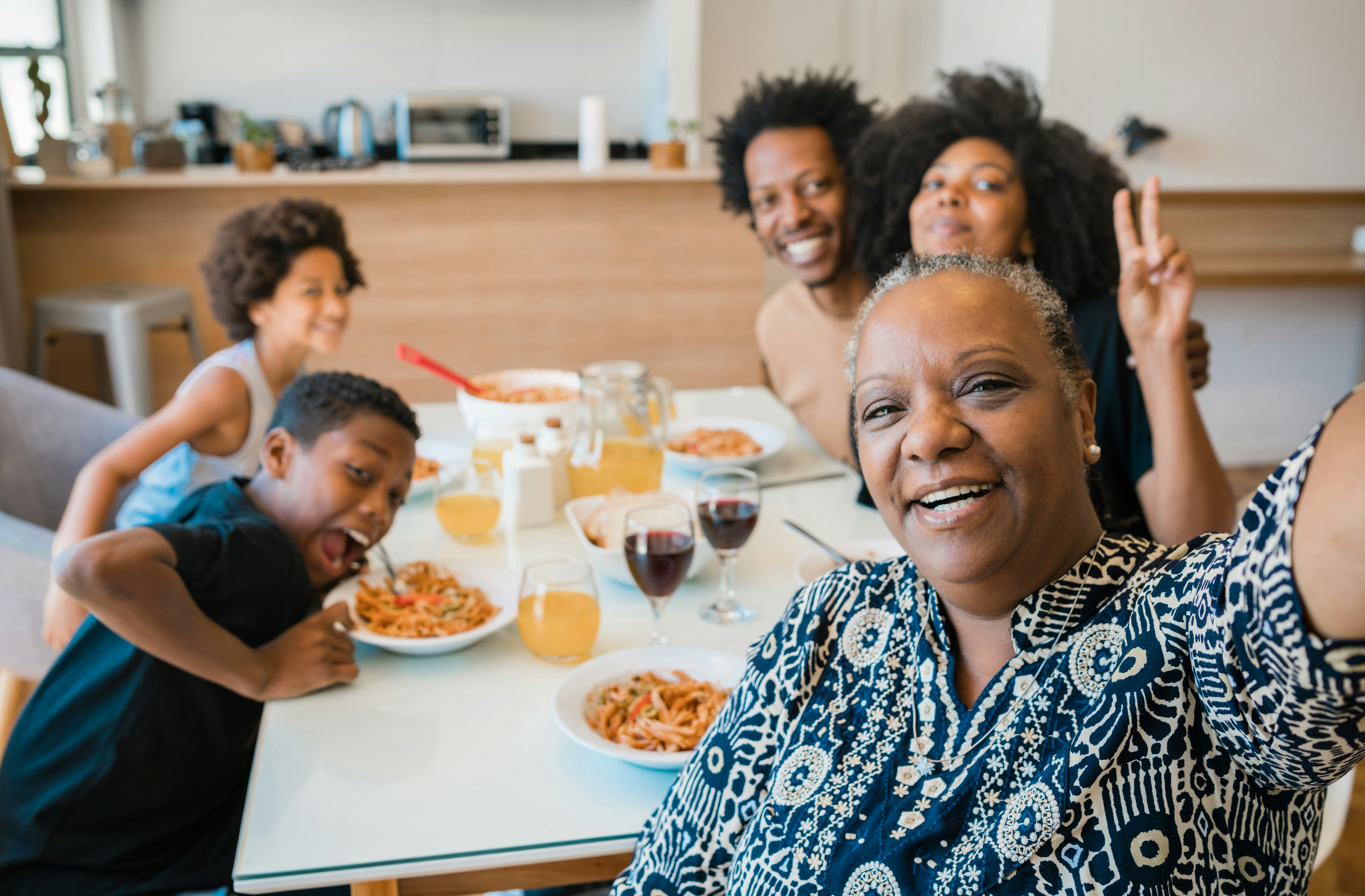 Family Meal Gathering A joyful family gathering around a dining table filled with plates of food, drinks, and smiling faces.