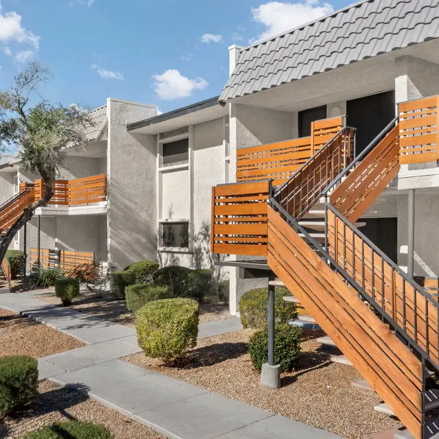 View of an apartment complex with two-story buildings and wooden staircases.