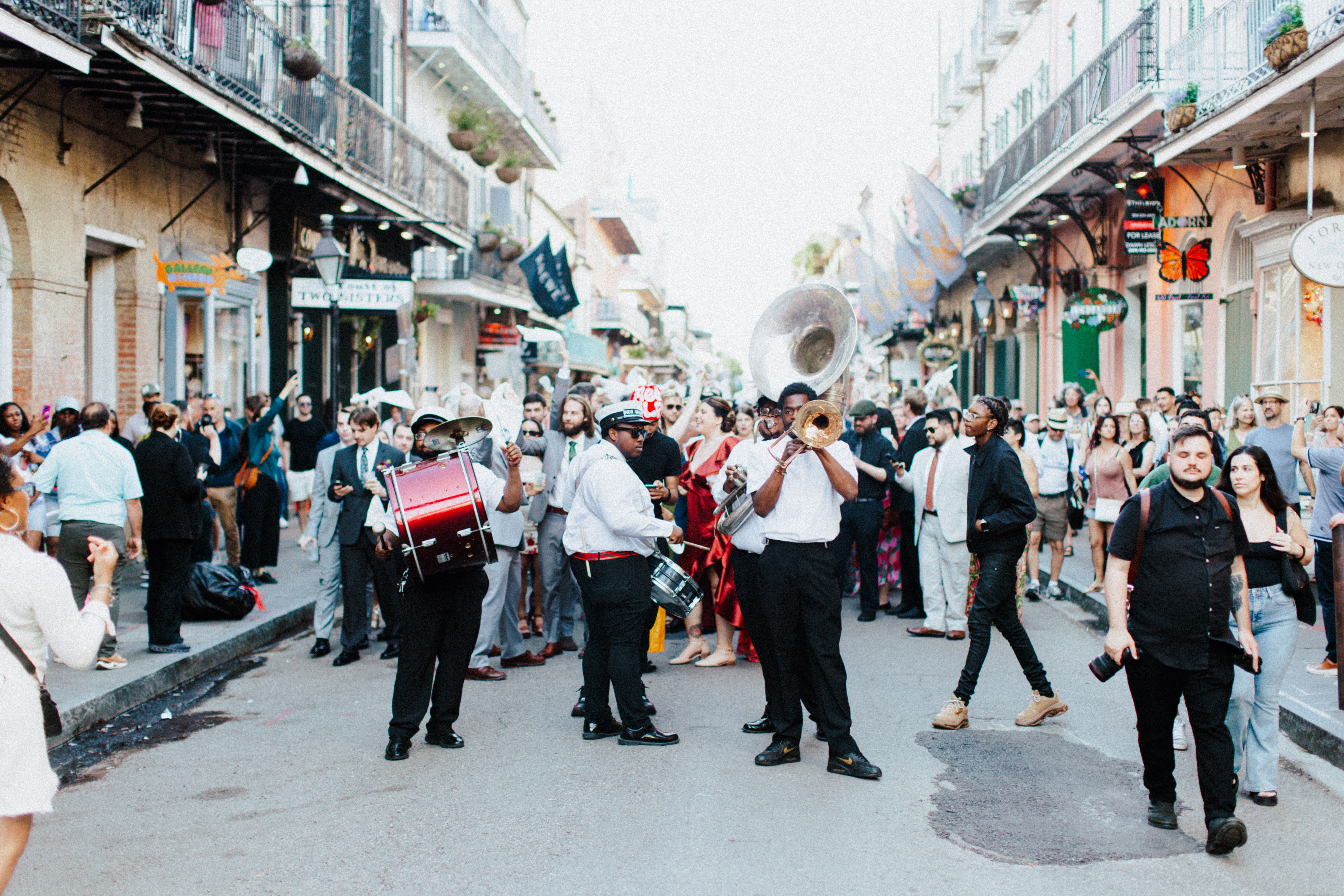 A lively street scene in New Orleans with a brass band playing, surrounded by a crowd of people enjoying the event.