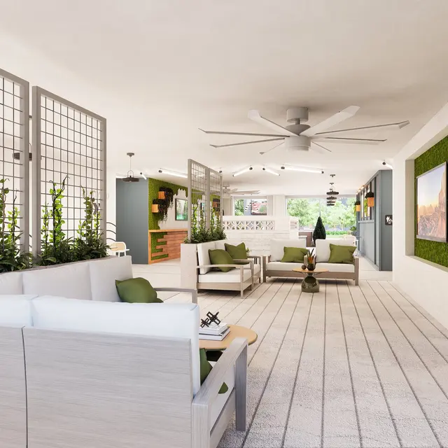 A modern indoor lounge area featuring comfortable seating, greenery, and wall-mounted artwork.