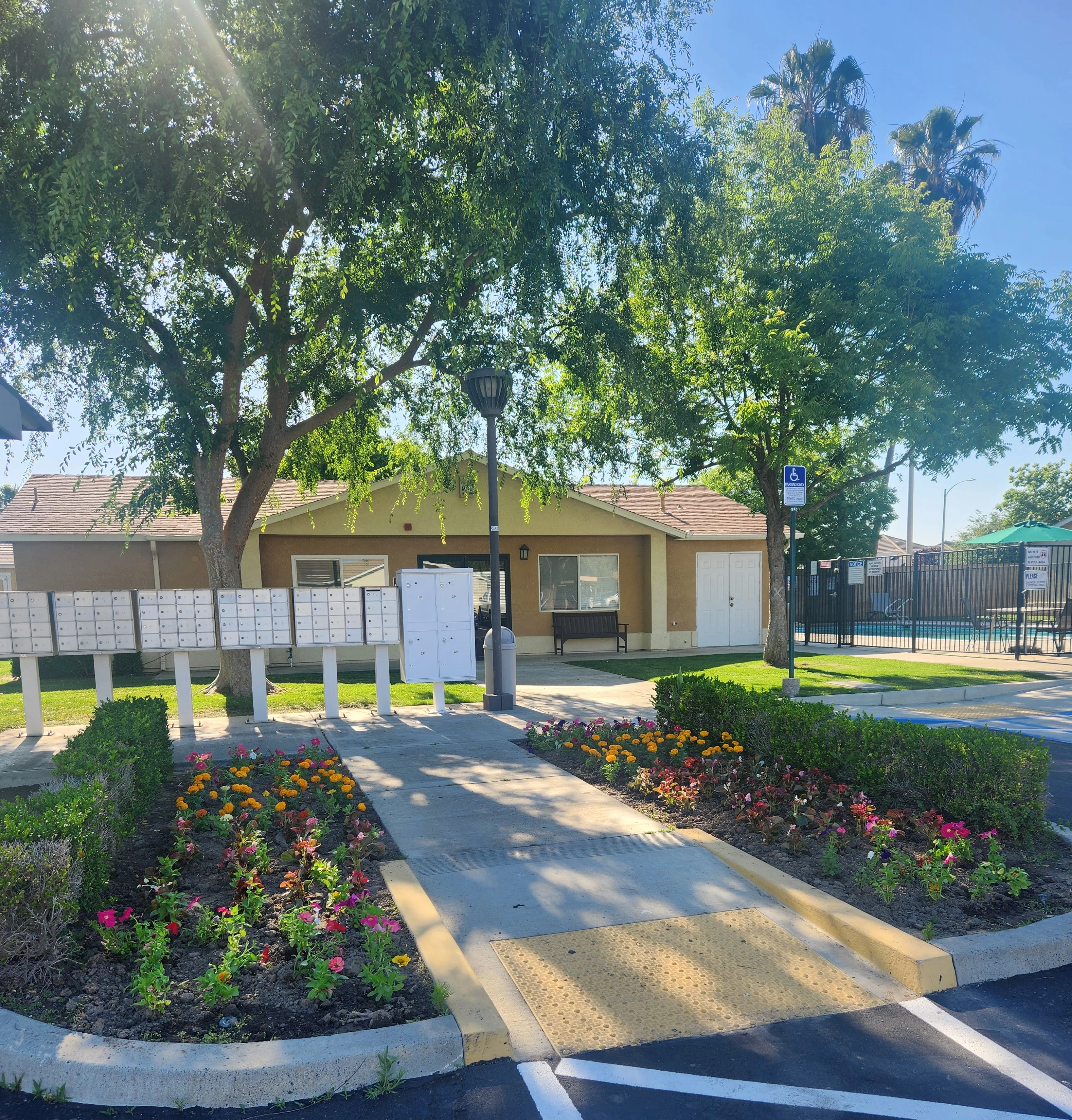 Residential Mailbox Area A well-maintained outdoor area featuring a row of mailboxes, colorful flower beds, and surrounding trees in a residential setting.