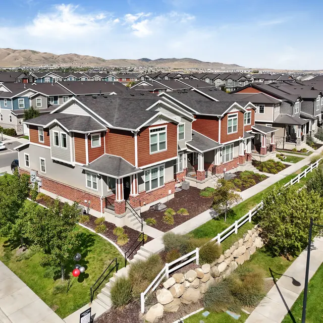 An aerial view of a modern housing development with multi-story homes and a landscaped street.