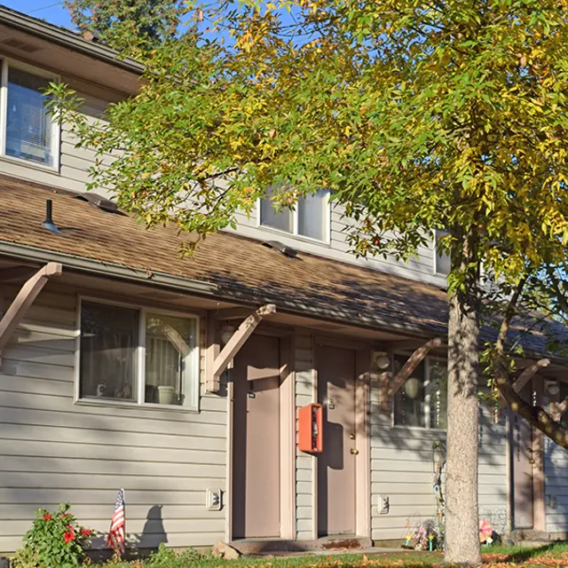 Residential Building Exterior Front view of a two-story residential building with a tree in the foreground and a well-maintained yard.