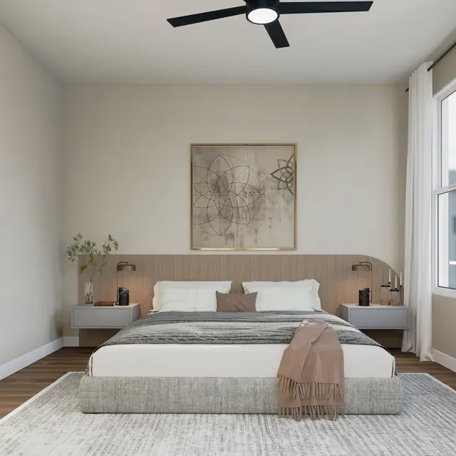 A modern bedroom featuring a bed with light bedding, a wooden headboard, and side tables. The decor includes a wall art piece and a small plant. A ceiling fan is visible, and there's natural light coming through a window.