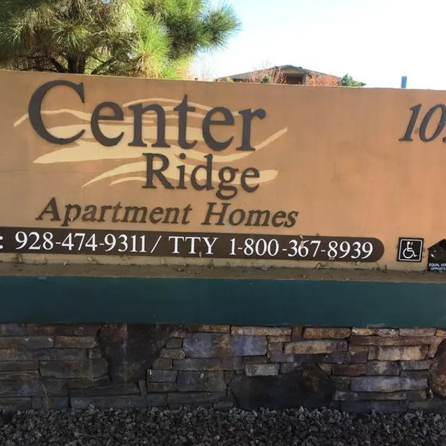 Center Ridge Apartment Homes Sign A sign displaying the name and contact information for Center Ridge Apartment Homes. The sign features a stone base and is set against a backdrop of greenery.
