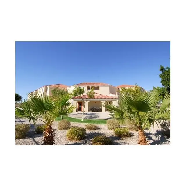 Charming Two-Story Home A large two-story house surrounded by palm trees and landscaped gravel areas under a clear blue sky.