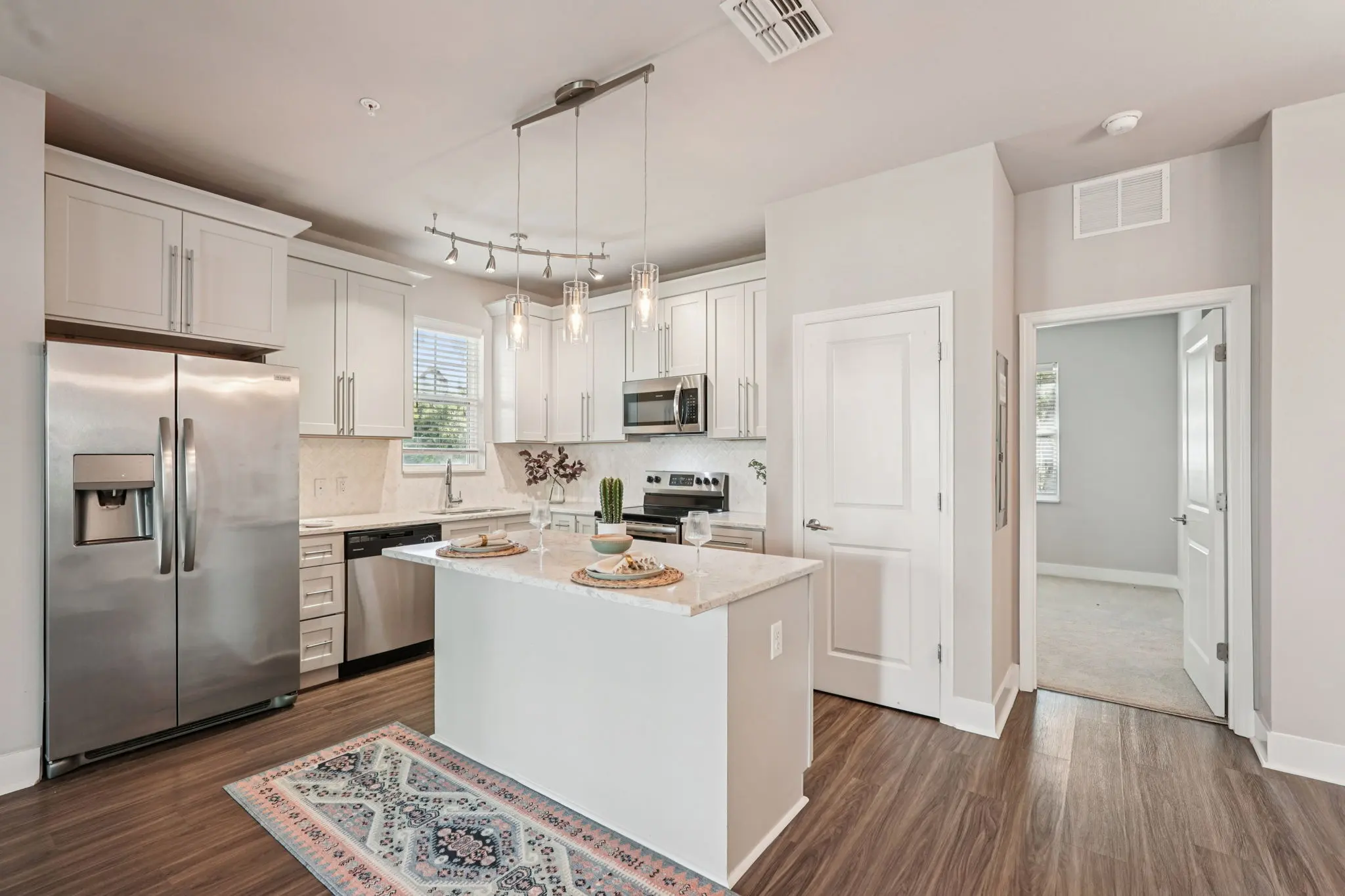 A modern kitchen featuring an island, stainless steel appliances, and ample natural light from windows.