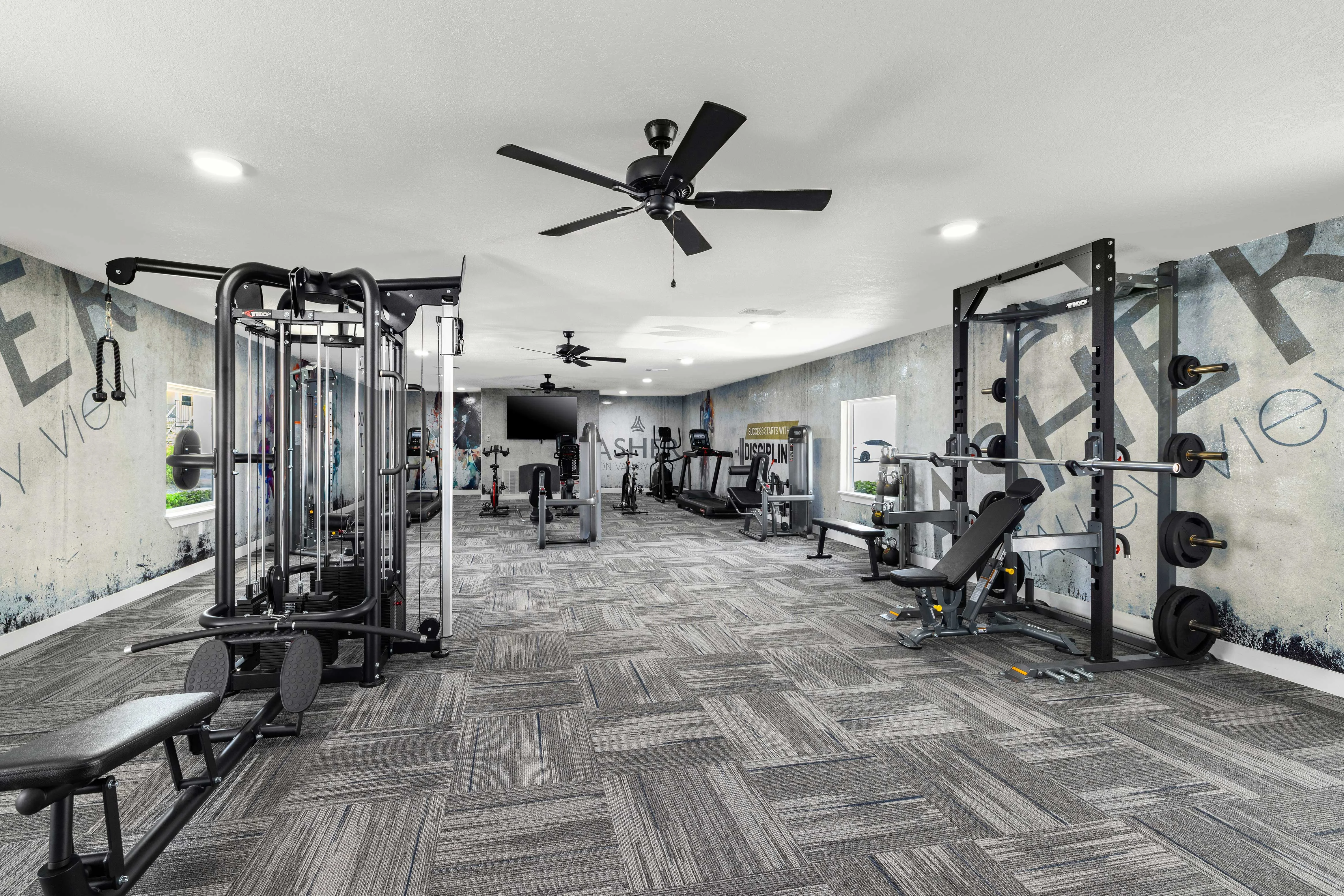 Modern Gym Interior A spacious and modern gym interior featuring various fitness equipment, including weight machines and benches, with a stylish wall design and fans on the ceiling.