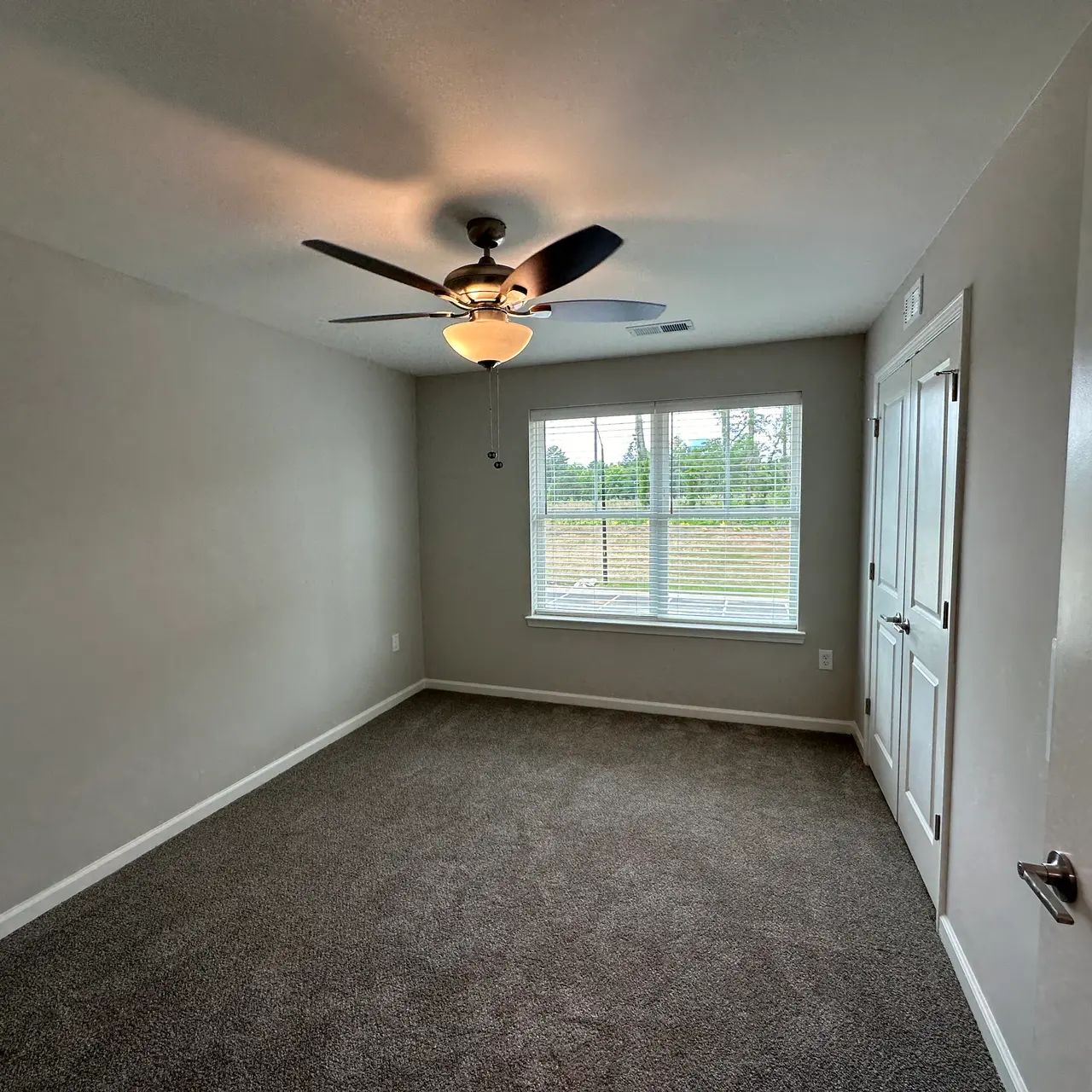 An empty bedroom featuring a ceiling fan and a large window