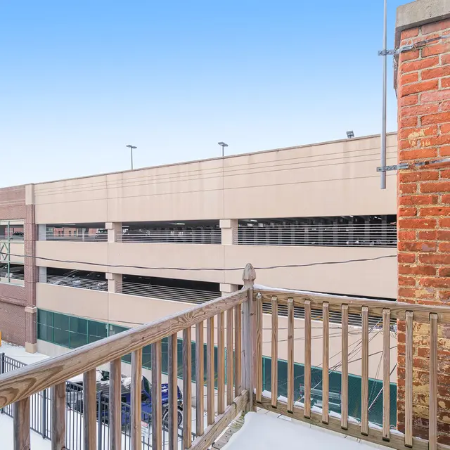 View from a balcony overlooking a parking structure with a clear blue sky