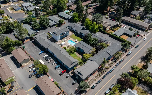 Aerial View of Apartment Complex Aerial view of an apartment complex with a central pool area surrounded by buildings and parking spaces.