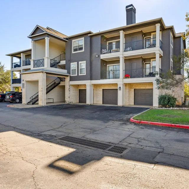 Exterior view of a modern multi-unit apartment building with balconies and a parking area.
